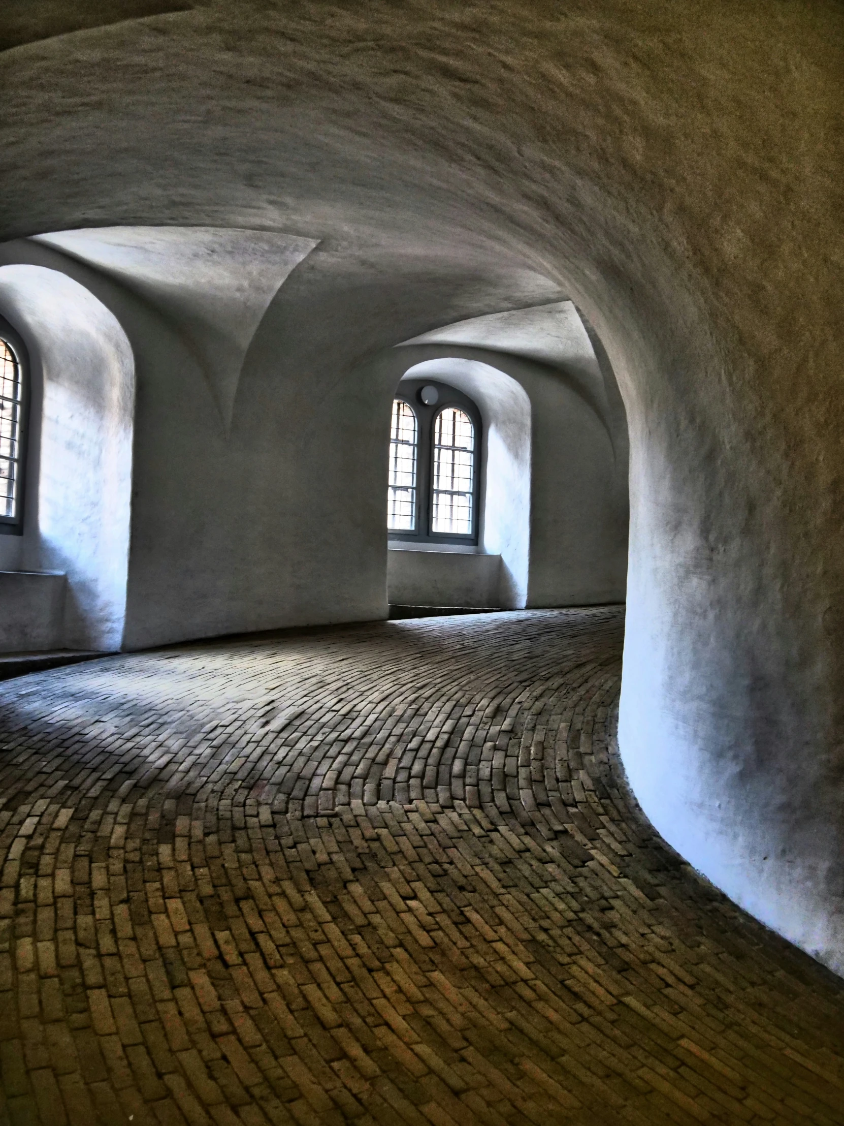 large arched windows in the middle of a cobblestone brick walkway