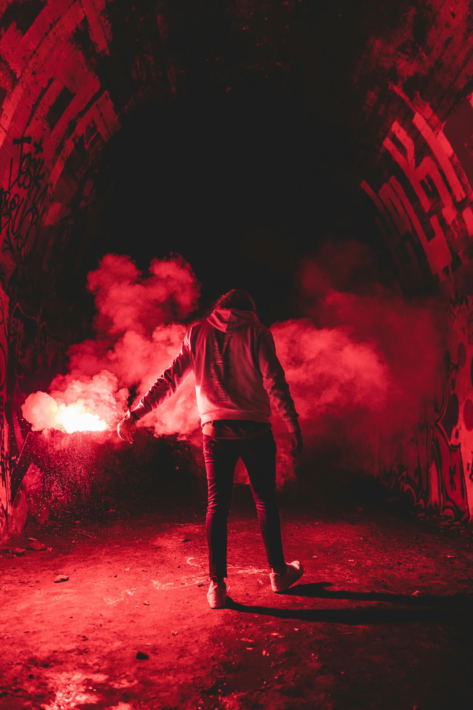 a man in a hooded jacket walking away from fire