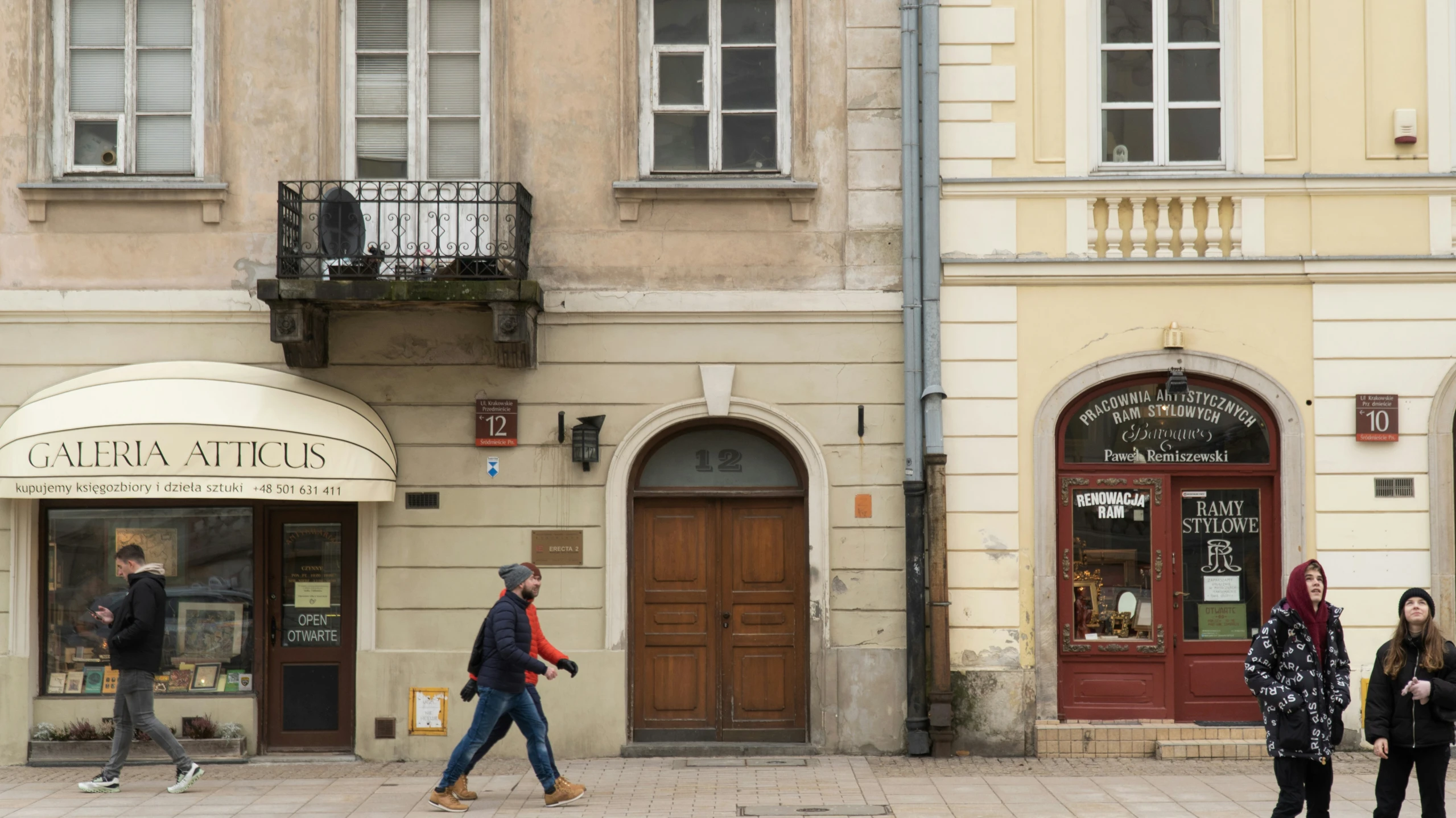 people walking down a street in front of several buildings