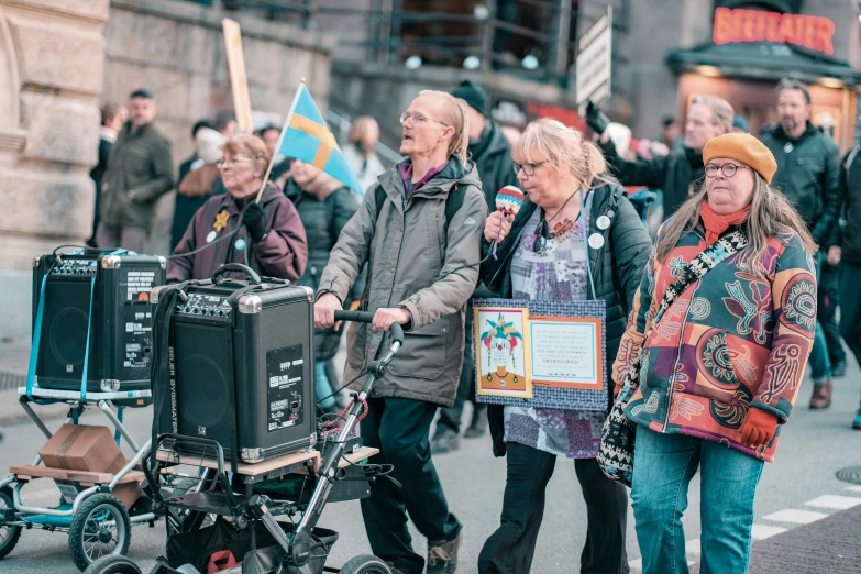 people standing on the side walk, with a baby stroller