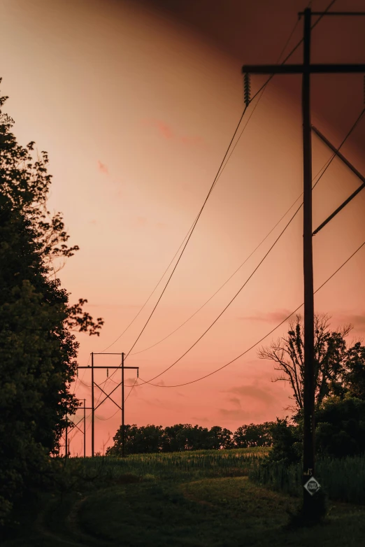 a red sunset and power lines in the distance