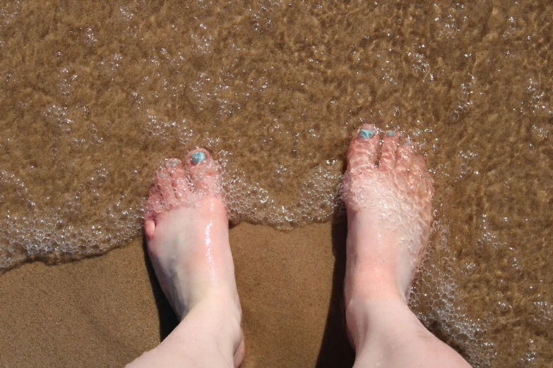 legs covered in white water near a sandy shore