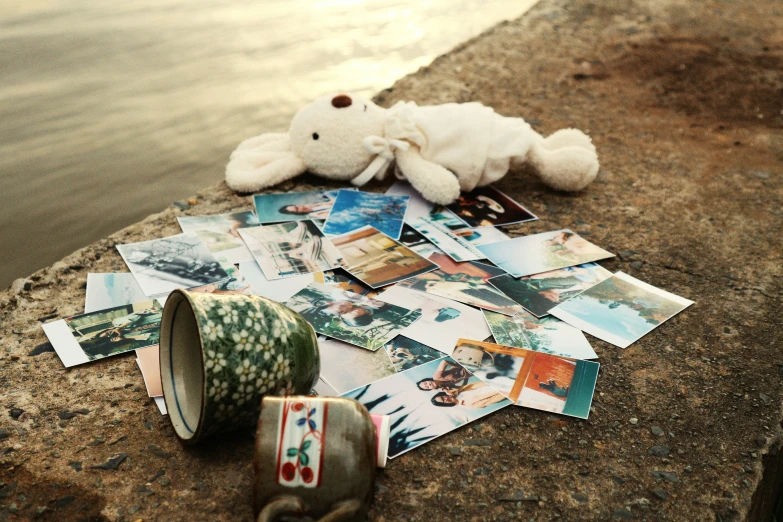a teddy bear and mug on the ground next to a river