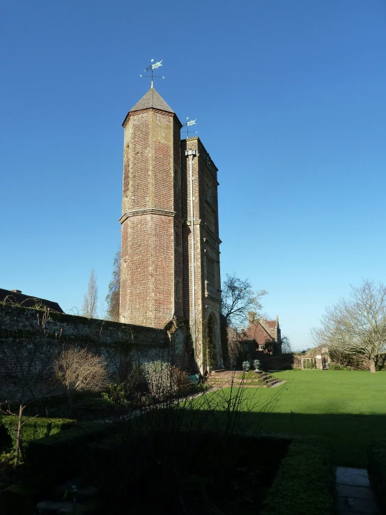 an old, tall brick tower stands in the grass