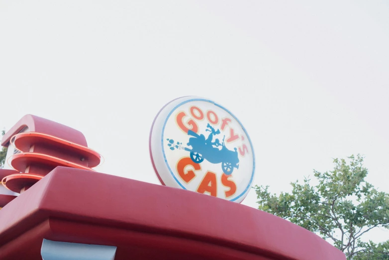 a red sign for gooyy's gas with some trees in the background