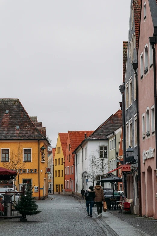 two people walking down the street with a truck parked nearby