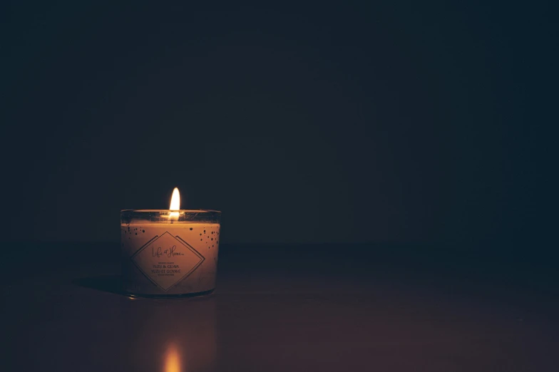 a white lit candle on a dark surface