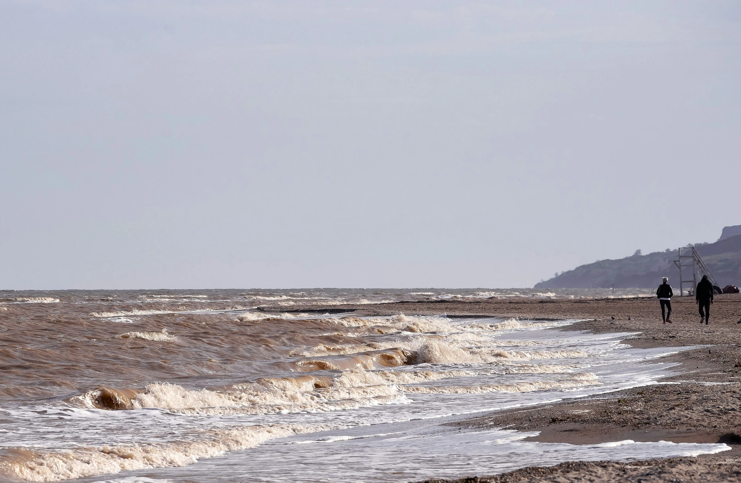 there are two people walking together near the beach