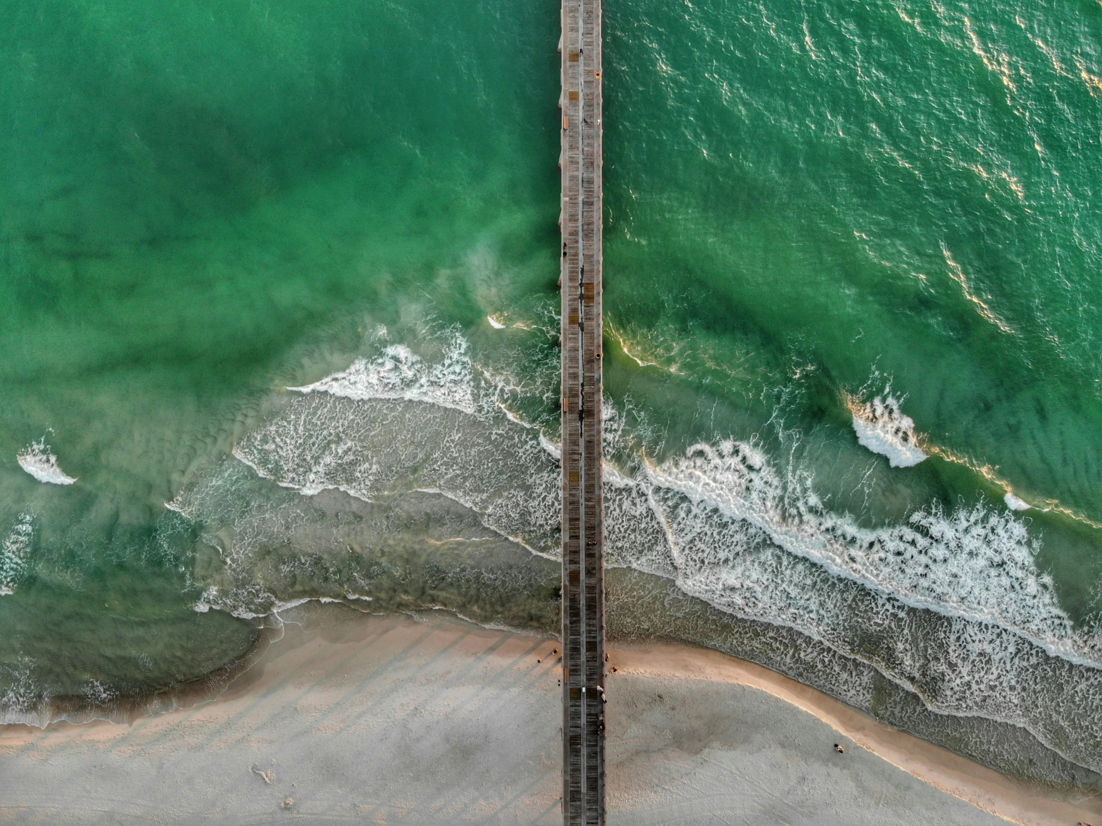 the aerial view of the ocean with a boardwalk near the beach