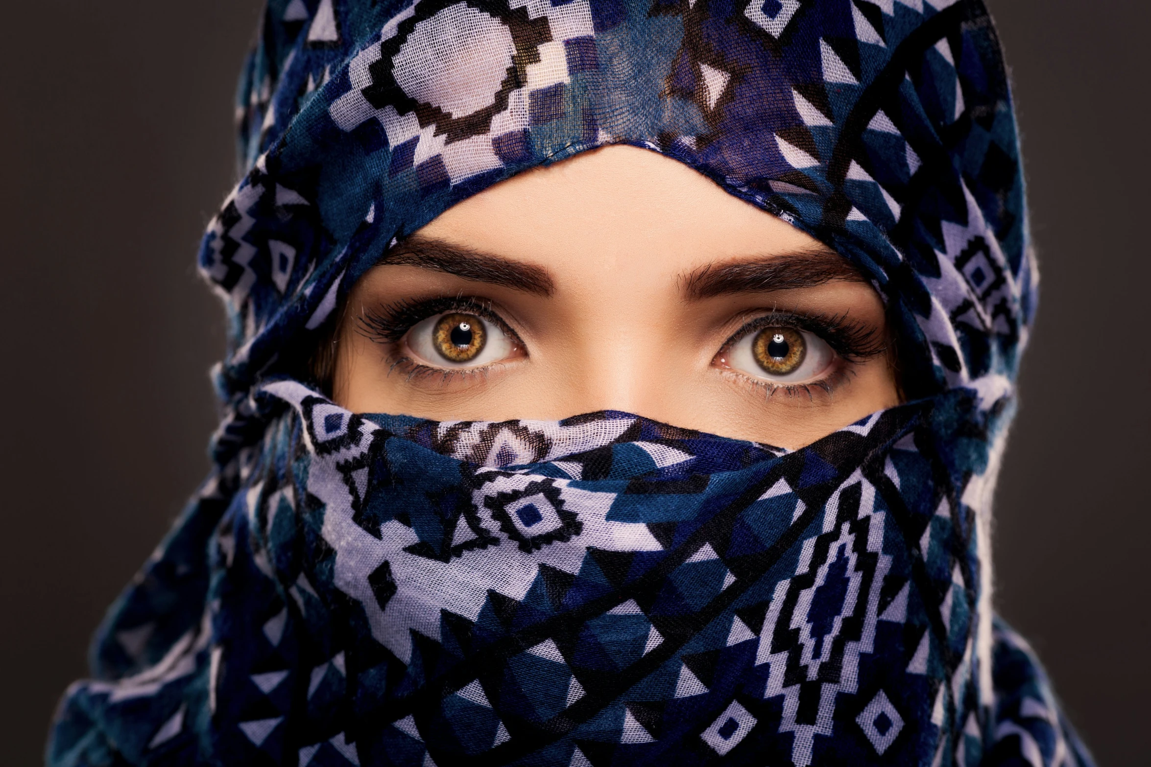 a beautiful young woman wearing a blue, patterned head scarf