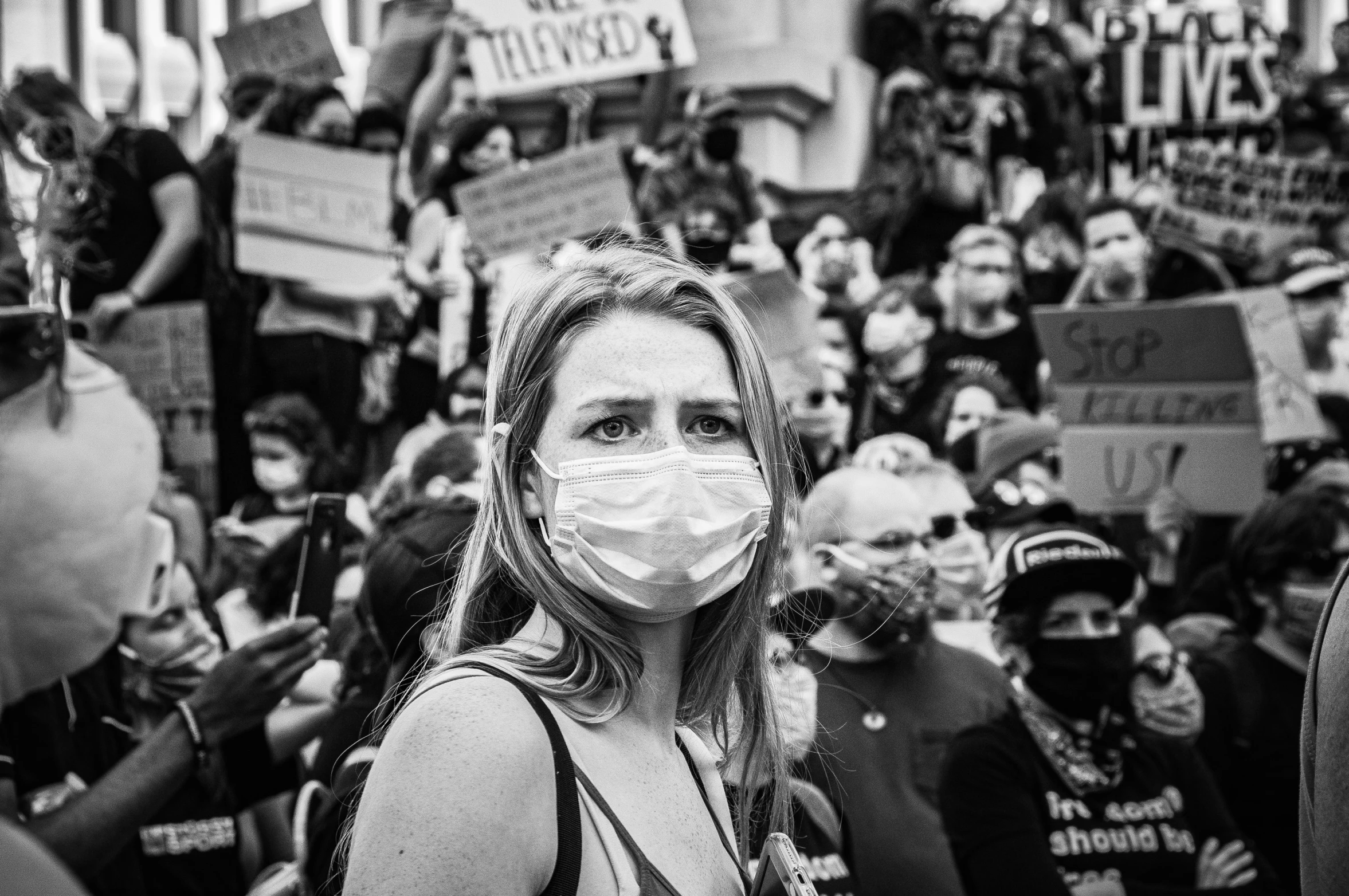 a black and white po of a woman with a protective face mask in a crowd