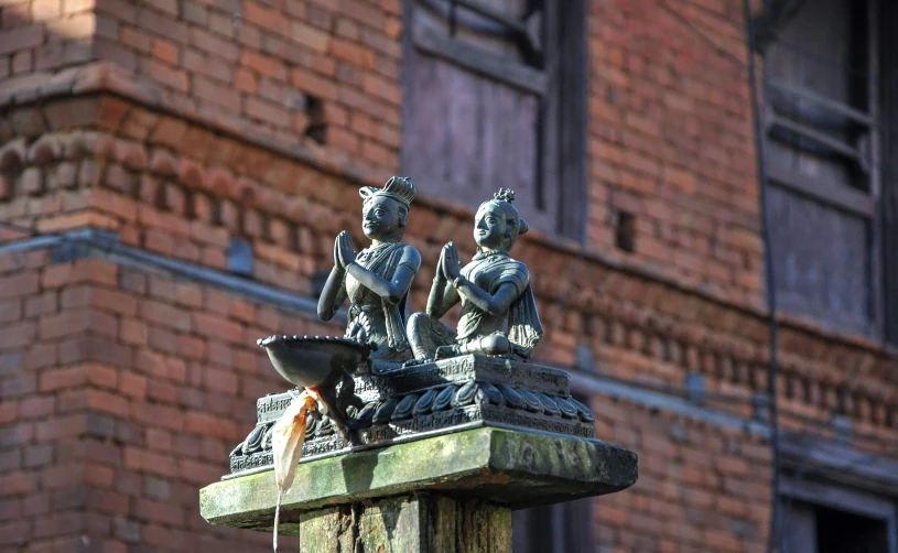 statue outside a brick building with a fountain