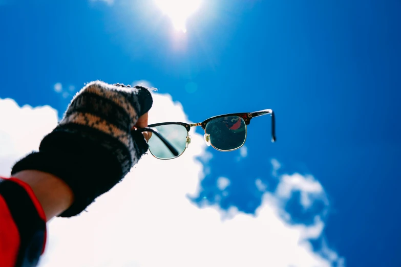 a pair of sunglasses that are held up in the sky