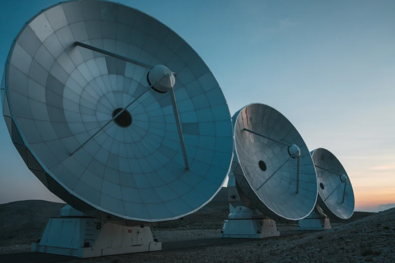 multiple large satellite dishes sit on concrete