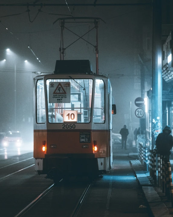 a yellow trolley traveling down train tracks under lights