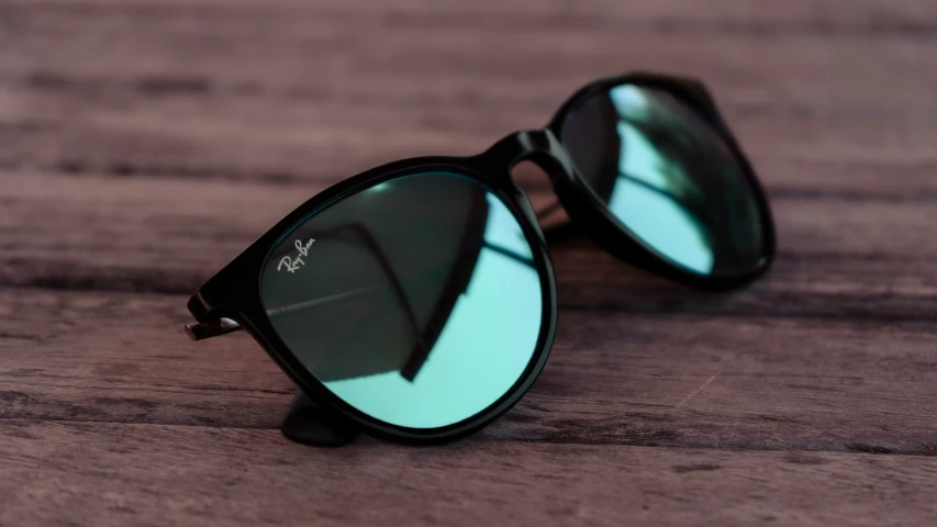 sunglasses sitting on a wooden surface with mirrored green lenses