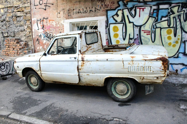 a dirty white truck parked next to a building