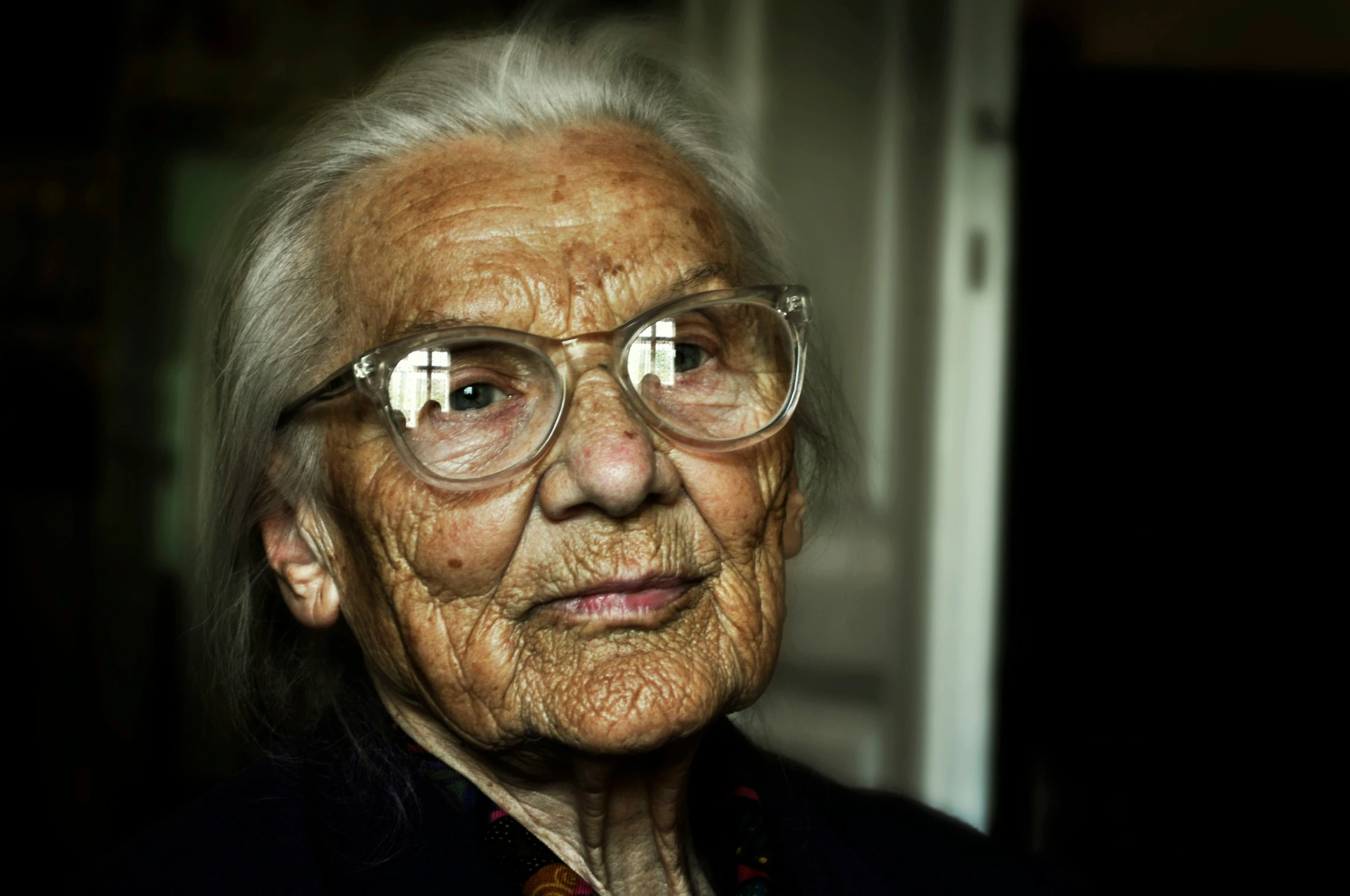 an old woman wearing glasses in the dark