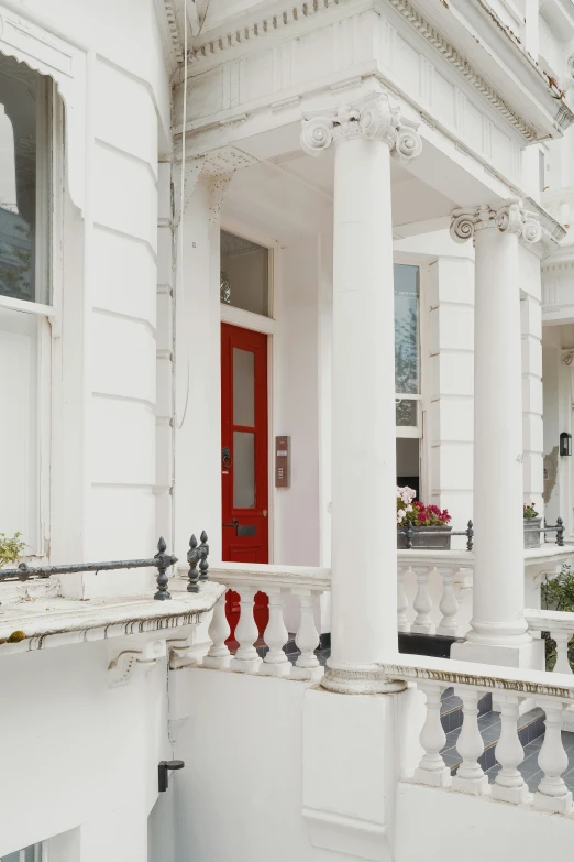 a house with columns, a red door and white porch