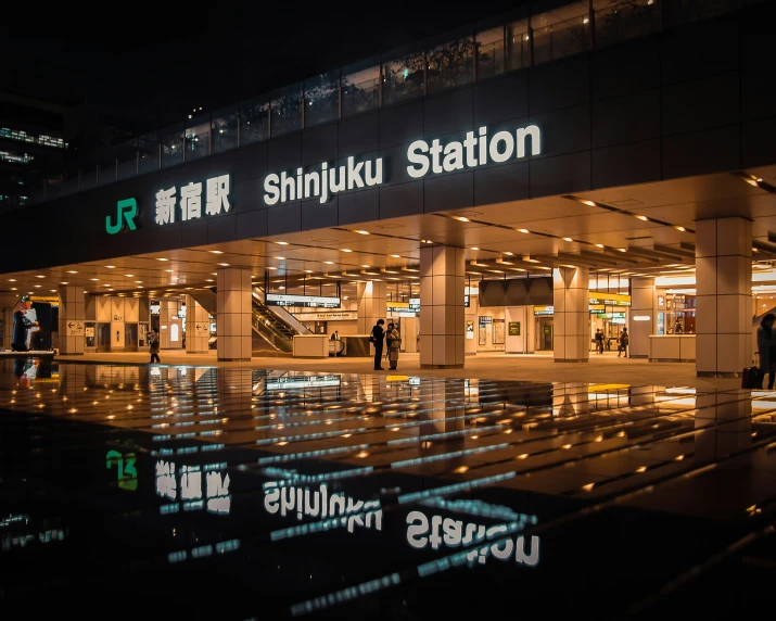 people walking in front of a station at night
