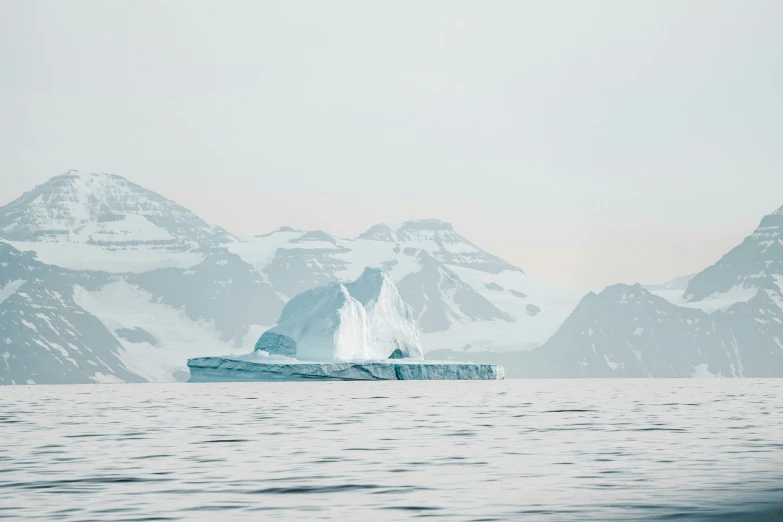 a giant iceberg in the middle of the ocean surrounded by mountains