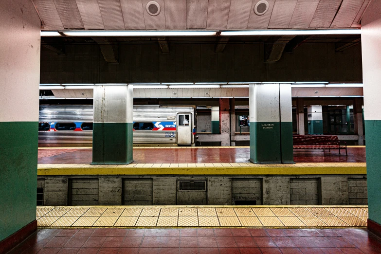 a subway station with empty benches and a train coming in