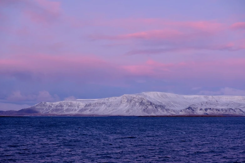 an island covered in snow under a pink cloudy sky