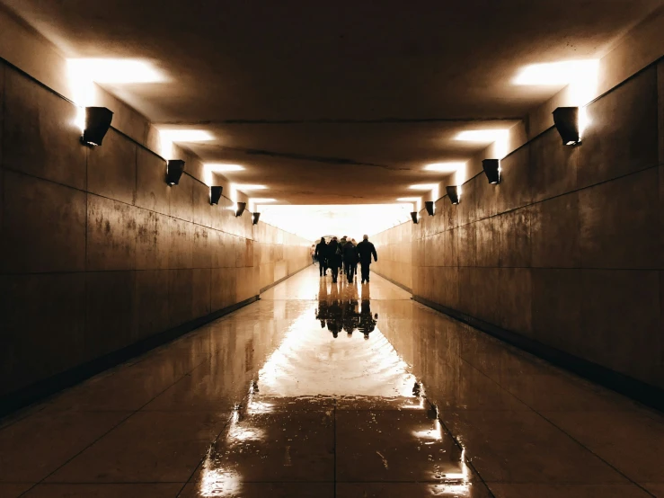 three people standing inside a tunnel under lights