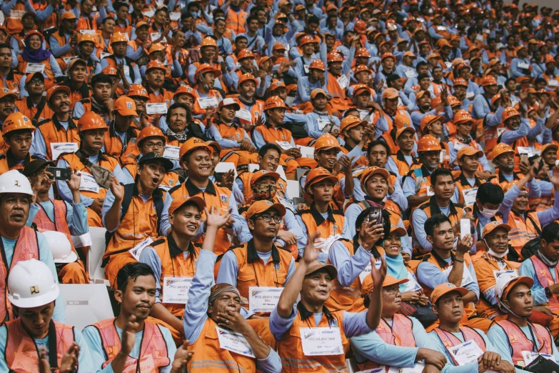 several people are seated on benches with orange vests