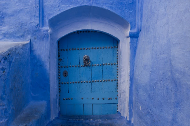 a blue door with metal rivets in an alley