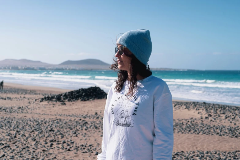 a young woman at the beach is wearing a beanie