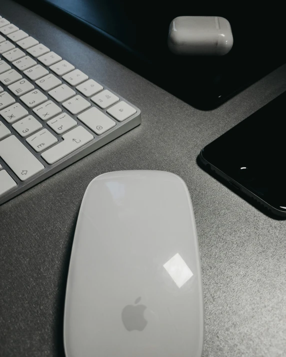 an apple mouse sits next to an iphone and mouse pad