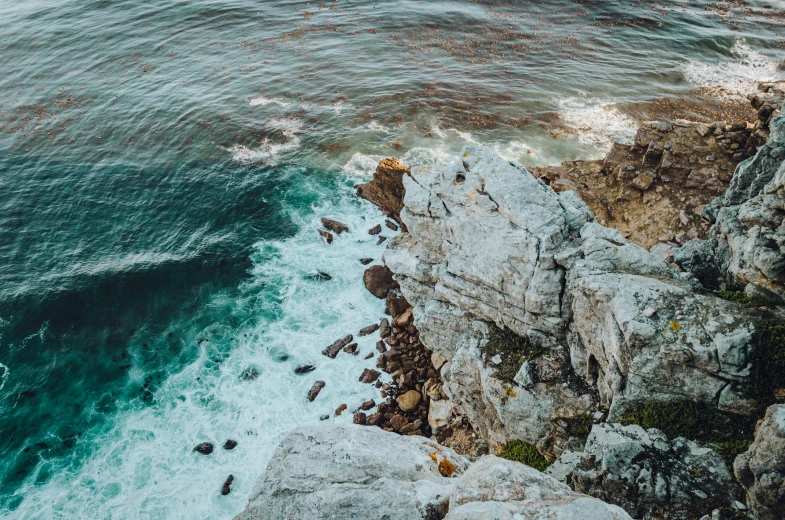 an aerial view of a cliff and ocean with many waves