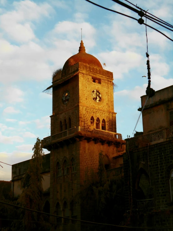 a clock tower seen through some wires at sunset