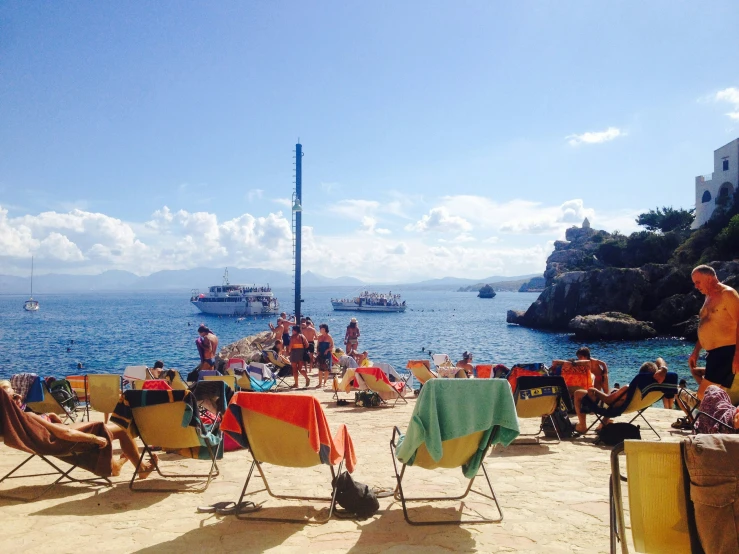 a crowded beach with people sitting and standing around