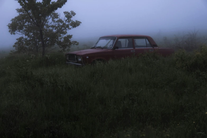 an old red car sitting in the grass