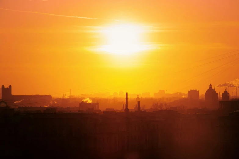 the sun setting on an overcast day and hazy city