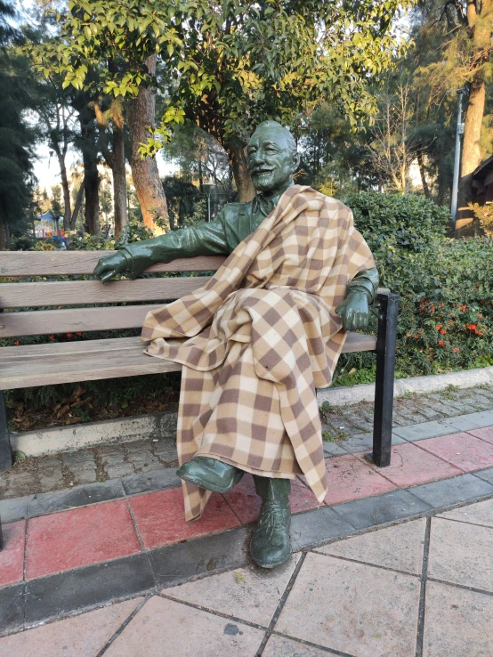 a statue of a man sitting on top of a wooden bench