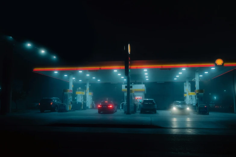 cars driving in front of a gas station at night