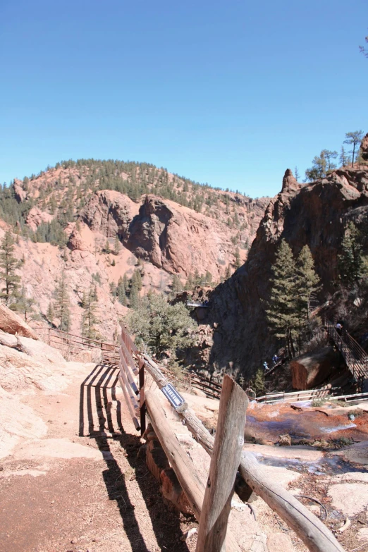 a wooden trail that has a rocky cliff