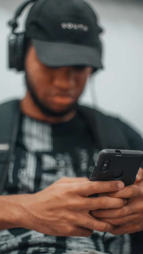 the man is wearing headphones, looking at his cell phone