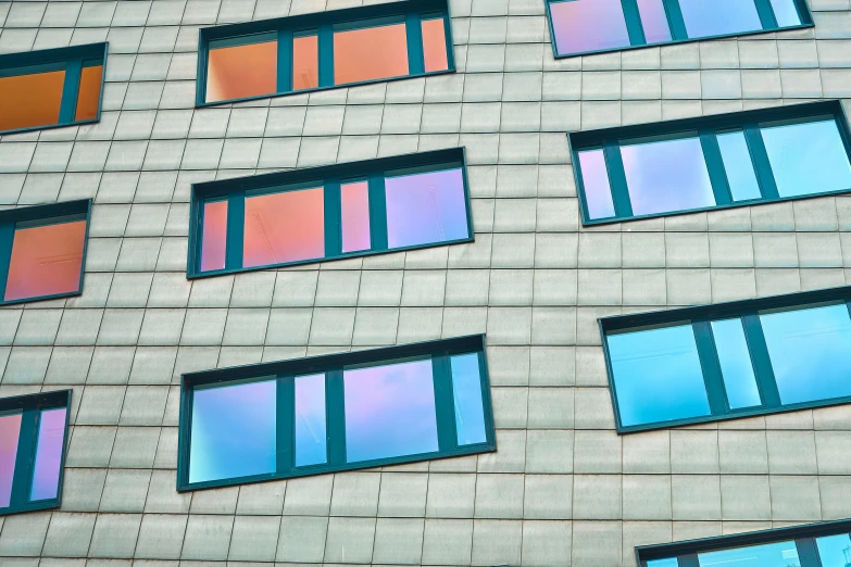 several windows of various color sitting on the side of a building
