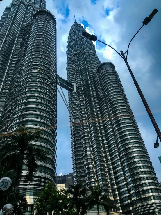 two tall, slender skyscrs against a cloudy blue sky