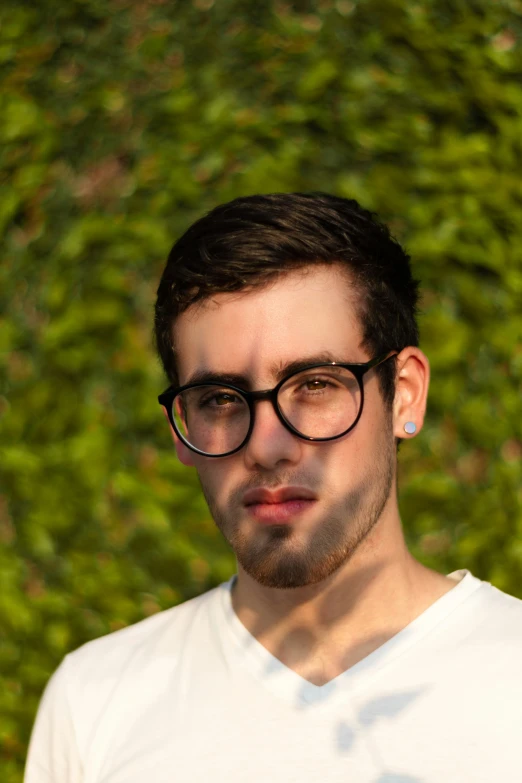 the man is staring ahead while wearing a white t - shirt