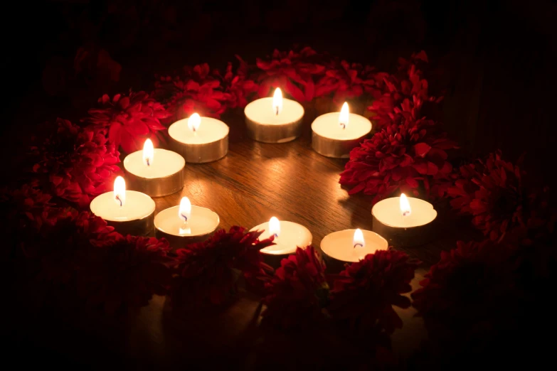 candles arranged in a circle in front of a rose bush