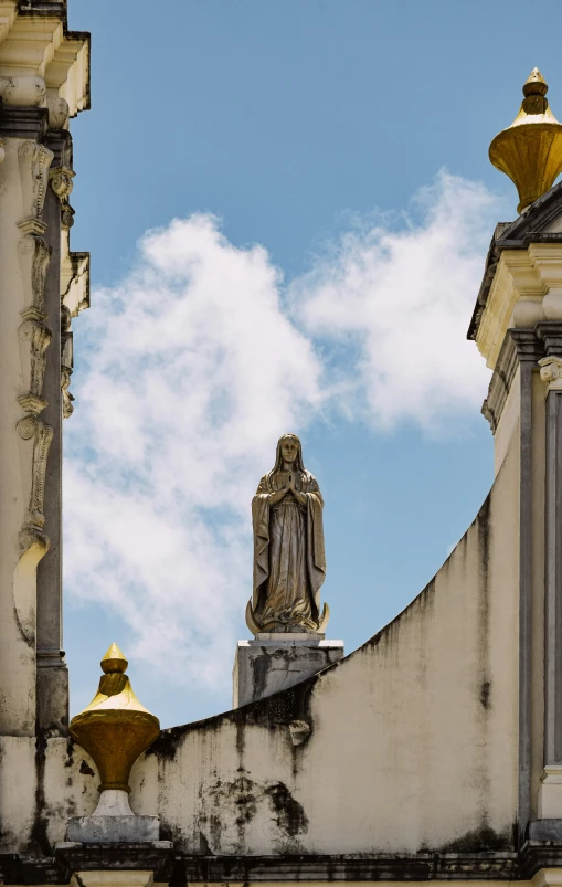 a statue of a man and two towers, with clouds in the background