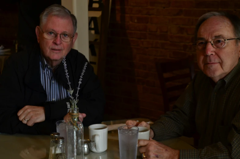 two older men sitting at a table with their coffee cups