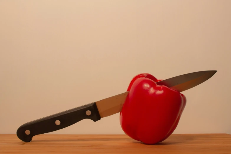 a large knife is  a red apple