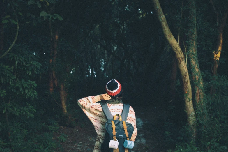 the person in a hat is standing by a tree