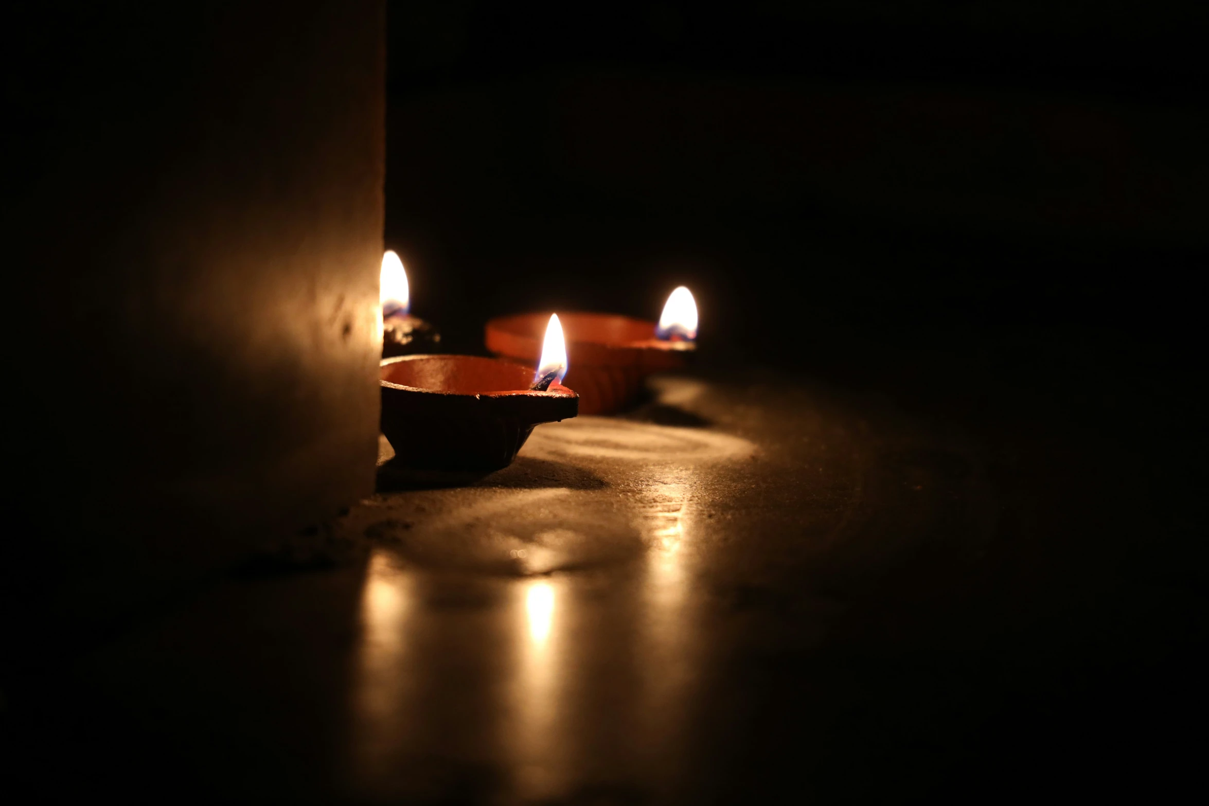 three candle lights are glowing up on the floor